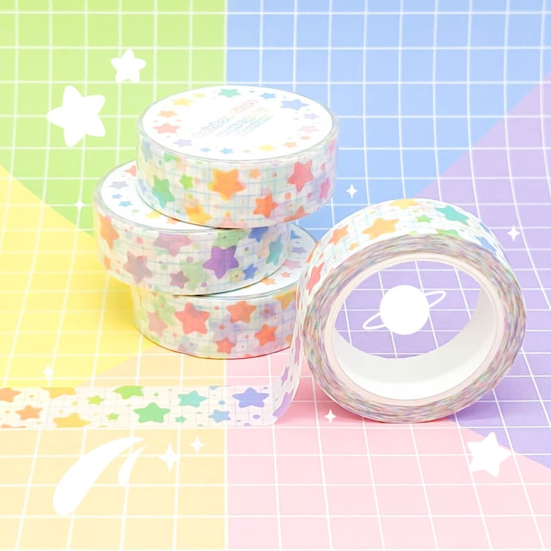 May include: Four rolls of colorful washi tape with a rainbow star pattern. The tape is on a pink and blue grid background.