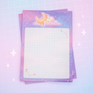 May include: Two notepads with a celestial design. The top notepad has a grid pattern and a border of stars and constellations. A cartoon crescent moon, clouds, and stars decorate the top. The colour scheme is pastel purple, pink, and yellow.