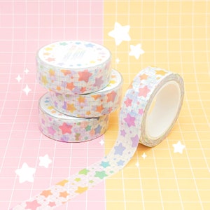 May include: Three rolls of washi tape with a pastel rainbow star pattern on a white background. The tape is unrolled and shows the pattern.