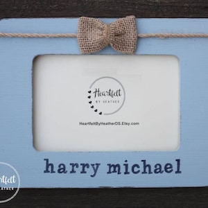 May include: Light blue wooden picture frame with a burlap bow and the text "harry michael" on the bottom. The frame has a white mat and a clear window for a photo.