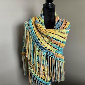 May include: A crocheted shawl with a colorful striped pattern and fringe. The shawl is made in shades of blue, green, yellow, and orange.