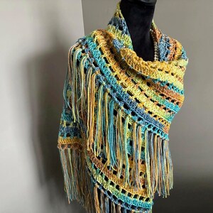 May include: A crocheted shawl with a fringe border in shades of blue, green, and yellow.