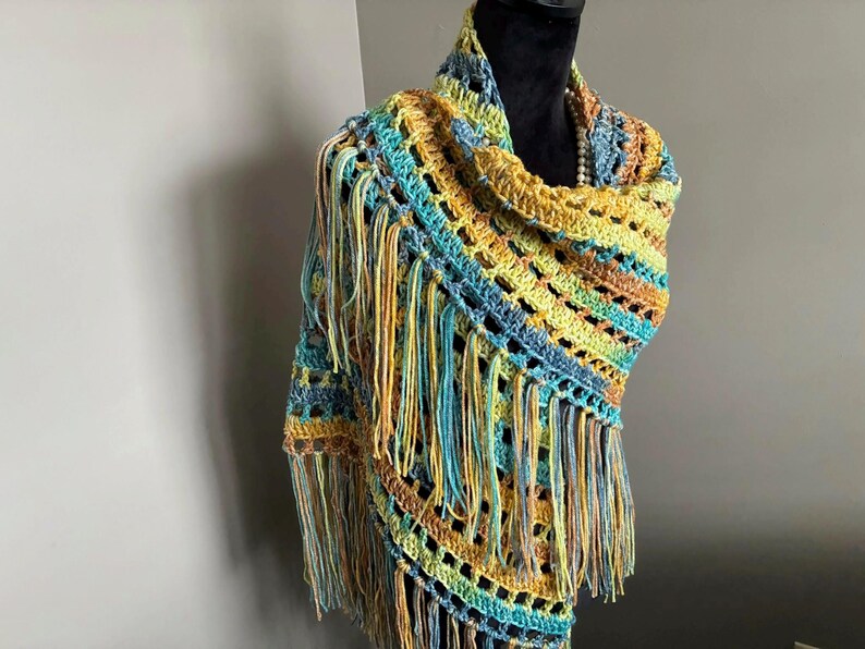 May include: A crocheted shawl with a fringe border in shades of blue, green, and yellow.