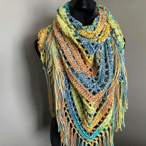 May include: A crocheted triangular shawl with a multi-colored pattern of blue, green, yellow, and orange. The shawl has long fringe around the edges.