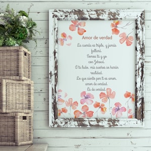May include: A framed print with a distressed white frame. The print features watercolor flowers in shades of orange and purple. The text in Spanish reads "Amor de verdad" and a poem about love.