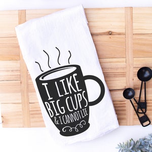 May include: White tea towel with a black and white illustration of a coffee mug with steam coming out of it. The text on the towel reads "I like big cups & I cannot lie."