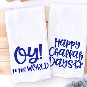 May include: Two white kitchen towels with blue text. One towel says "Oy! to the world" and the other says "Happy Challah Days" with a blue Star of David.