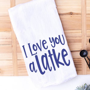 May include: White kitchen towel with the text "I love you a latke" in blue lettering.