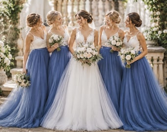 May include: A group of five individuals wearing floor-length gowns with white lace bodices and blue tulle skirts. The central figure wears a white lace gown with a full skirt. Each individual holds a bouquet of white and cream flowers.