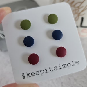 May include: Six round stud earrings in olive green, navy blue, and burgundy, presented on a white card. The card features the text "keep it simple" and the hashtag #keepitsimple.