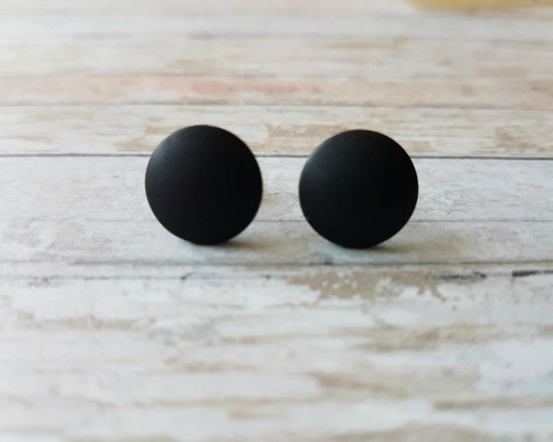 May include: A pair of black stud earrings. The earrings are round and have a matte finish.