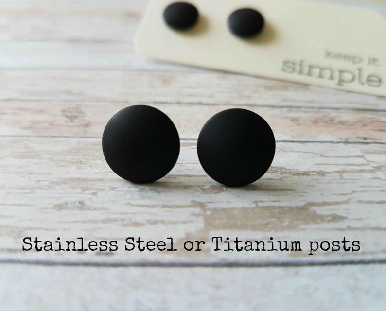 May include: A pair of black stud earrings with a matte finish. The earrings are made of stainless steel or titanium.
