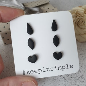 Puede incluir: Un juego de seis pendientes de botón negros en forma de lágrima, hoja y corazón. Los pendientes se muestran en una tarjeta blanca con el texto "#keepitsimple".