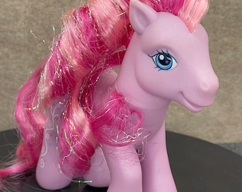 May include: A pink My Little Pony toy with long, pink and white hair with glitter. The pony has blue eyes and a pink body.