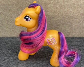 May include: A yellow My Little Pony toy with pink and purple hair. The pony has a butterfly symbol on its flank.
