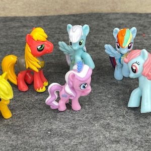 Könnte beinhalten: Eine Sammlung von sechs kleinen Plastik-Pony-Figuren. Die Ponys sind in verschiedenen Farben, darunter Gelb, Rot, Rosa, Blau und Weiß. Sie haben verschiedene Frisuren und Markierungen.