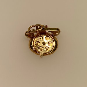 May include: A gold-tone rotary phone charm with a detailed design. The charm has a loop at the top for attaching to a necklace or bracelet.