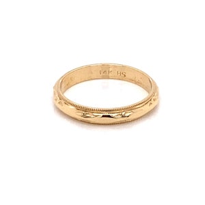 May include: A simple gold wedding band with a textured design. The band is marked "14K HS".