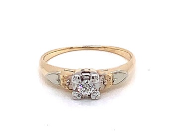 May include: A gold engagement ring with a single diamond set in a white gold prong setting. The band is a tri-color design with yellow gold, white gold, and rose gold.