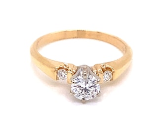 May include: A gold engagement ring with a single round diamond and two smaller diamonds on the band.