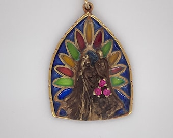 May include: A gold pendant with a stained glass design featuring a woman's face with three pink gemstones. The stained glass design has a blue, green, red, and yellow color scheme.