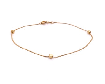 May include: A delicate gold anklet with three small round beads.