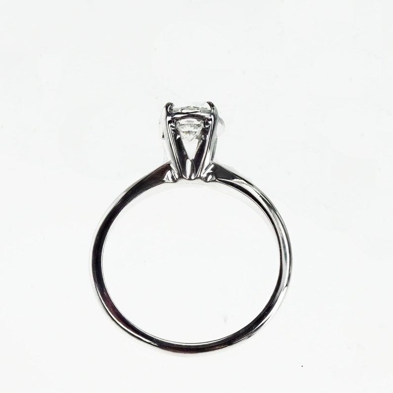 May include: A silver solitaire engagement ring with a round, clear diamond.