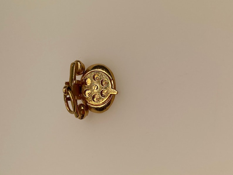 May include: A gold-colored charm in the shape of a rotary phone. The charm has a detailed design and is perfect for adding a vintage touch to a bracelet or necklace.