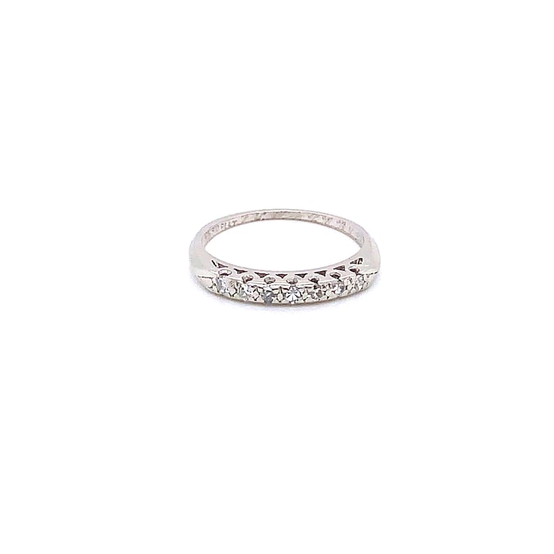 May include: A silver band ring with a row of small, clear diamonds set in the centre.