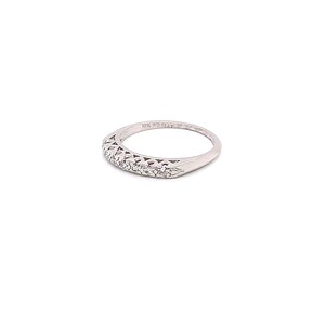 May include: A silver band ring with a row of small diamonds set in a delicate design. The ring is marked "14K Gold" on the inside.