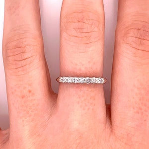 May include: A thin silver band with a row of small, clear diamonds set in a prong setting.