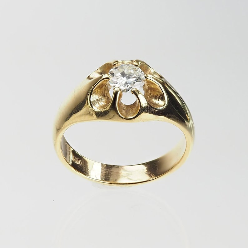 May include: A gold ring with a single round diamond set in a flower-shaped design. The ring is marked "14K" on the inside.