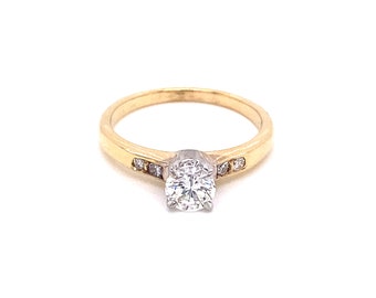 May include: A gold engagement ring with a single round diamond and a band of smaller diamonds.