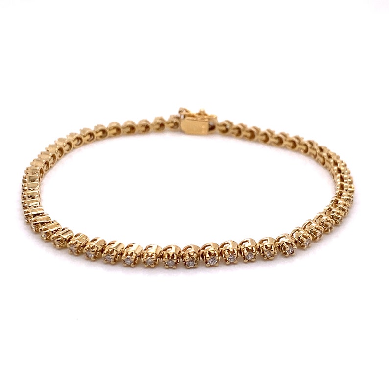 May include: A gold tennis bracelet with small round diamonds set in a continuous line.