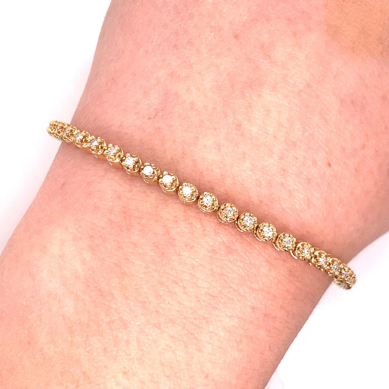 May include: A gold tennis bracelet with small round diamonds set in a pave setting.