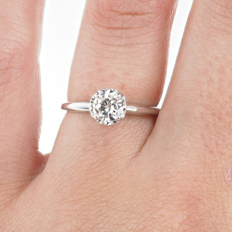May include: A simple solitaire engagement ring with a round brilliant cut diamond set in a white gold band.