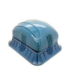 May include: A vintage, light blue magnetic aquarium cleaner. The cleaner has a rounded top with vertical ridges and a decorative base. The base has a repeating pattern of curved shapes. The cleaner is designed to clean the inside and outside of an aquarium.