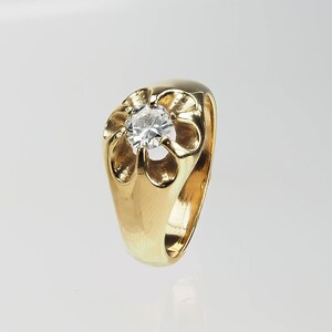 May include: A gold ring featuring a large, clear, round gemstone set in a flower-shaped design.