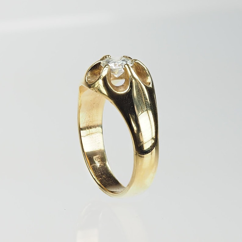 May include: A gold ring featuring a single, clear, round gemstone set in a distinctive, open-work design.