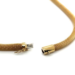 May include: A gold chain necklace with a woven mesh design. The necklace is open and the clasp is visible.