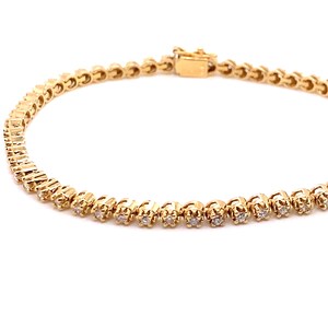 May include: A gold tennis bracelet with small round diamonds set in a delicate chain.