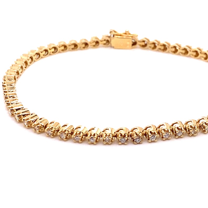 May include: A gold tennis bracelet with small round diamonds set in a delicate chain.
