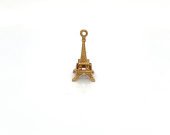 May include: A gold-colored Eiffel Tower charm pendant. The charm is detailed with intricate designs and has a loop at the top for attaching to a necklace or bracelet.