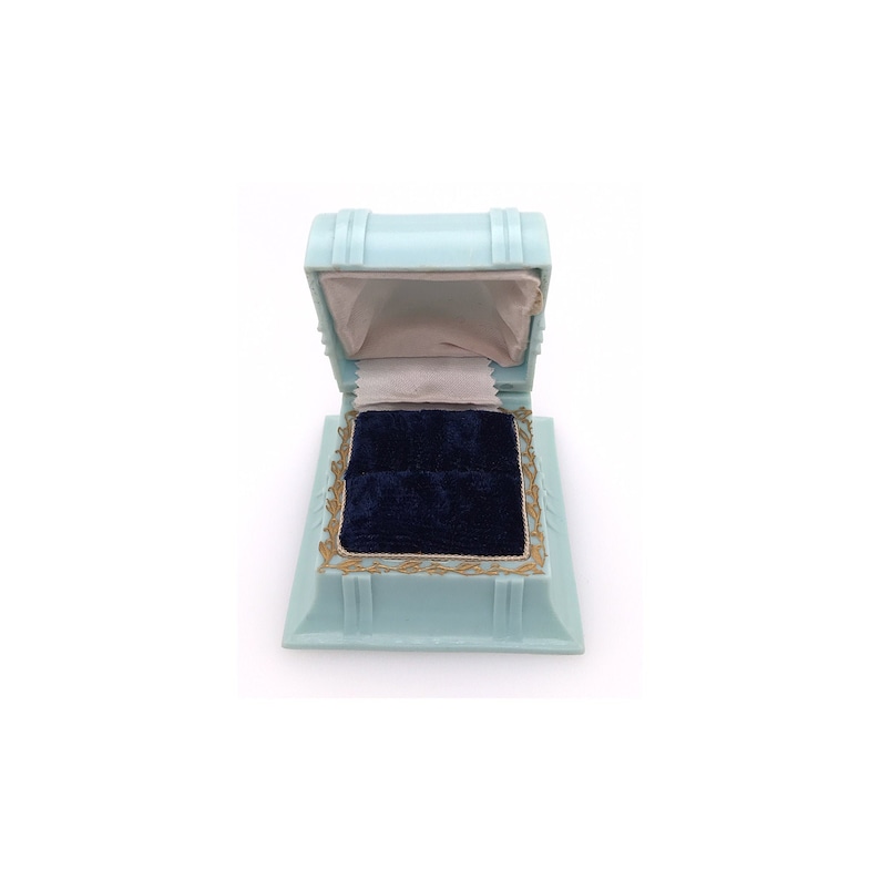 May include: A light blue ring box with a velvet interior. The box is open and the velvet is a dark blue color.