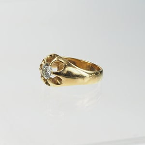 May include: A gold ring featuring a single round diamond set in an ornate, openwork design.