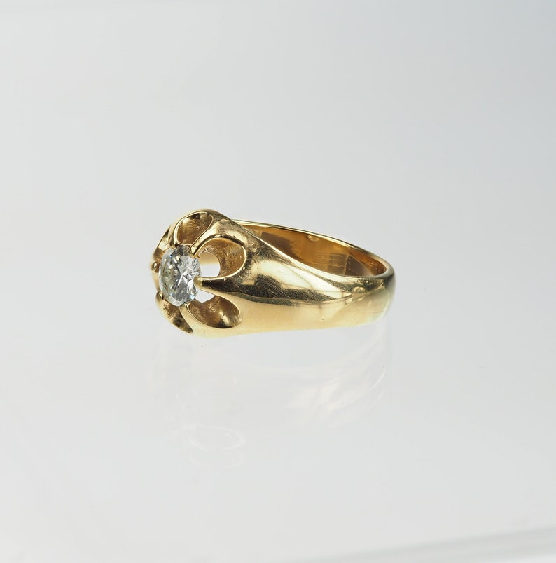 May include: A gold ring featuring a single round diamond set in an ornate, openwork design.