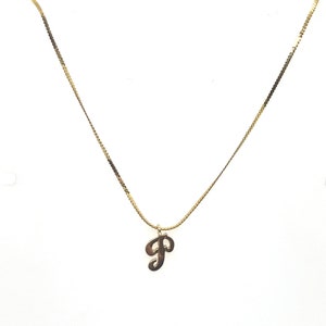 Op de afbeelding: Een gouden ketting met een hanger in de vorm van een cursieve letter 'P'.