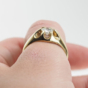 May include: A gold ring with a clear gemstone set in a unique, open design.