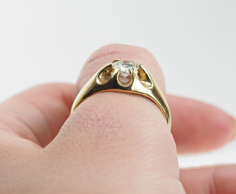 May include: A gold ring with a clear gemstone set in a unique, open design.