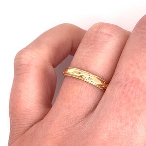 May include: A gold wedding band with a textured design.